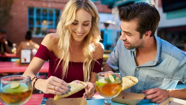 Man and woman at a restaurant eating tacos and drinking cocktails while enjoying each other's company